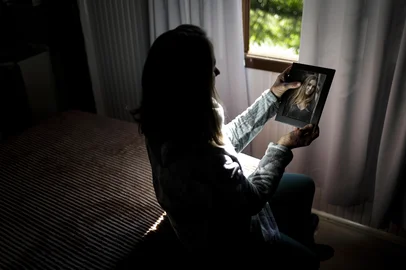 FELIZ, RS, BRASIL, 25-06-2025: A mãe, Marcia Elisa Müller, 61 anos, observa uma foto de Raíssa Müller, 21 anos, vítima de feminicídio na casa onde morava em Feliz, no Vale do Caí. Raíssa e o companheiro dela, Eric Richard de Oliveira Turato, 24, foram assassinados a facadas pelo ex-namorado dela em 18 de abril. O Rio Grande do Sul registrou 10 feminicídios no feriado de Páscoa, seis deles na Sexta-feira Santa. Agora, por pressão de deputadas gaúchas, o governo do RS deve recriar Secretaria da Mulher, extinta em 2015. Foto: Mateus Bruxel/Agência RBSIndexador: MATEUS BRUXEL<!-- NICAID(16067891) -->